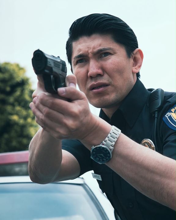 Action still of Medet in uniform aiming a prop sidearm